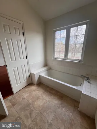 a spacious bathroom with a tub a sink and a window