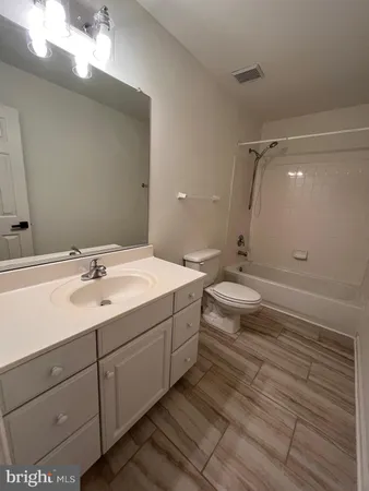 a bathroom with a double vanity sink and mirror with toilet