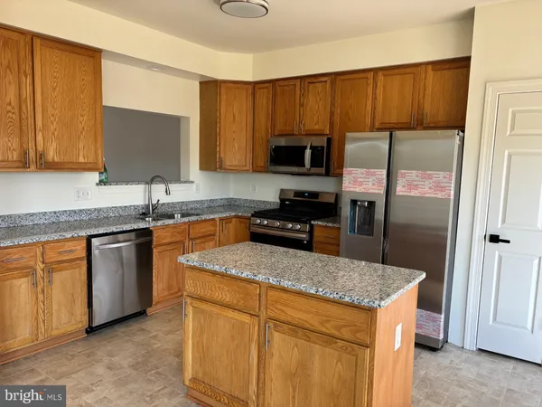 a kitchen with stainless steel appliances granite countertop a stove a sink dishwasher a refrigerator and a microwave