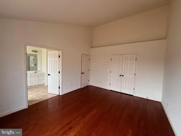 a view of empty room with wooden floor and white walls