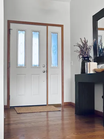 a view of an empty room with wooden floor and a potted plant