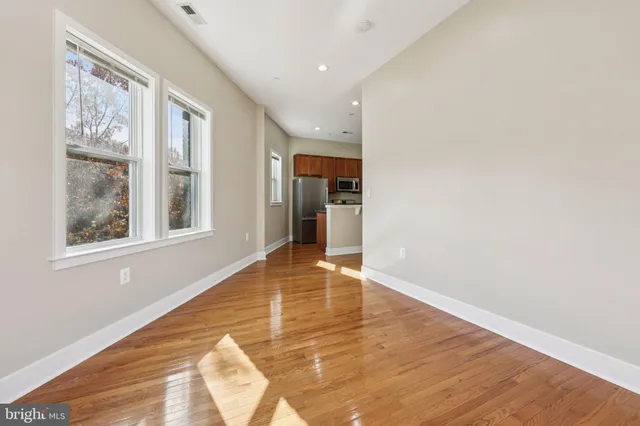a view of an empty room with wooden floor and a window