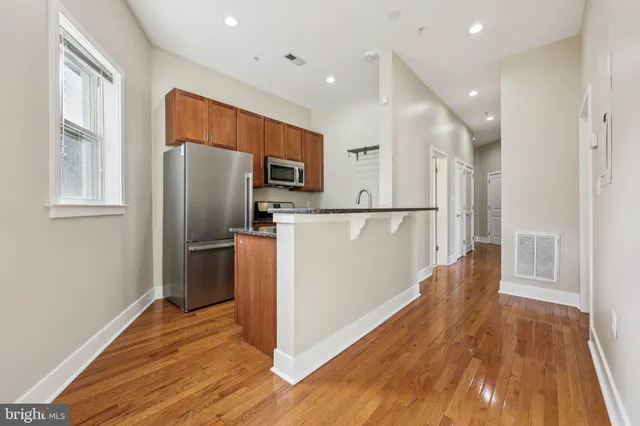 a kitchen with stainless steel appliances a refrigerator and wooden floor