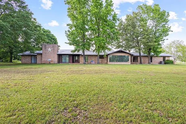 a view of a house with a big yard and large trees