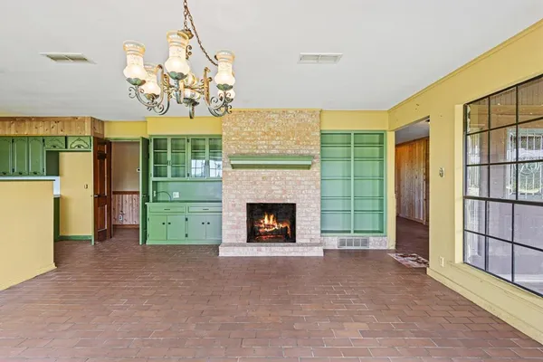 a view of a livingroom with a fireplace a chandelier and windows