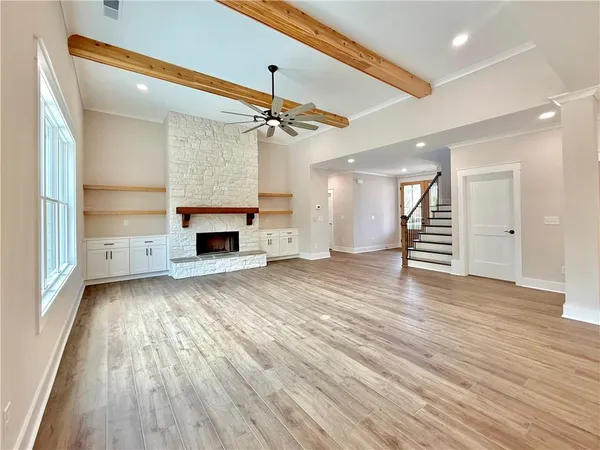 an empty room with wooden floor fireplace and windows