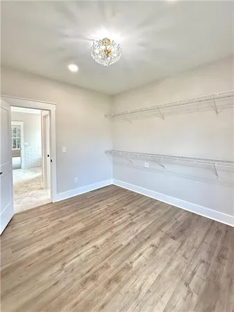 a view of empty room with wooden floor and kitchen view