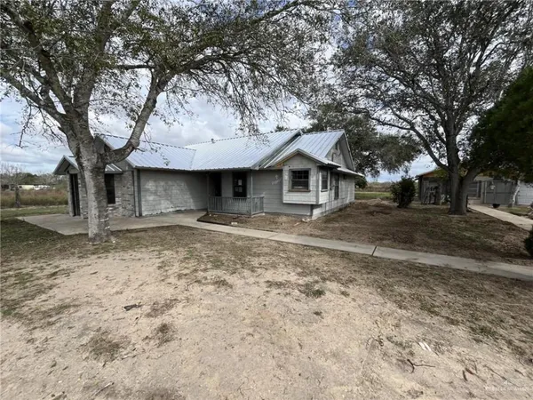a front view of a house with a yard and large tree