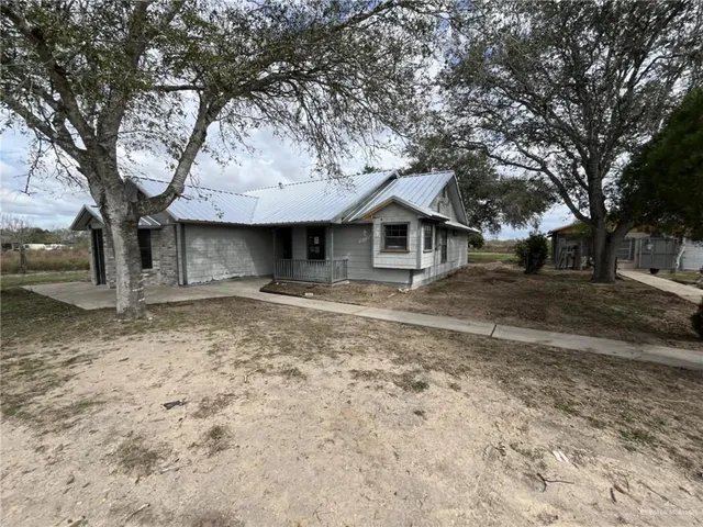 a front view of a house with a yard and large tree
