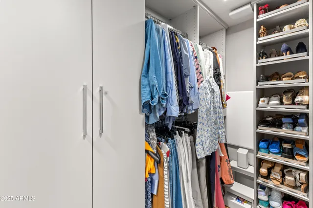 a view of walk in closet with clothes and shoes