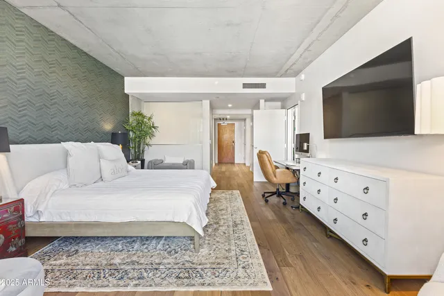 a large bedroom with a bed and flat tv screen on the dresser