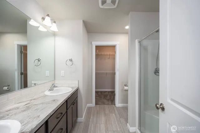 a spacious bathroom with a granite countertop sink a mirror and a shower