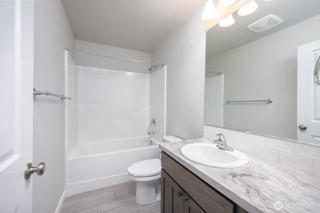 a bathroom with a granite countertop sink a toilet and shower
