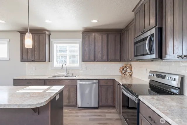 a kitchen with stainless steel appliances granite countertop a sink stove and microwave