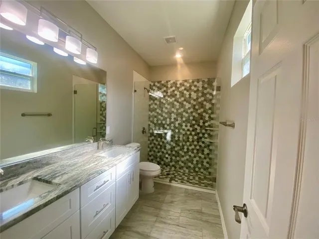 a bathroom with a granite countertop sink a toilet and shower