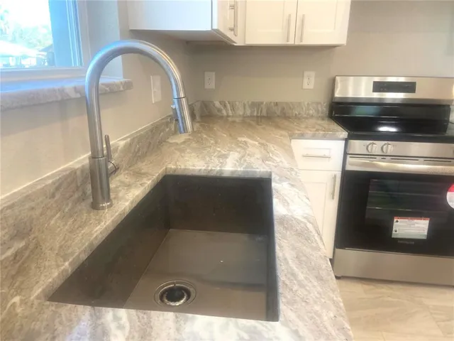 a kitchen with granite countertop a stove and a sink
