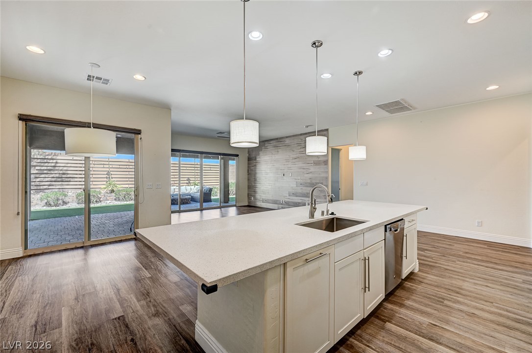 8197 Riley Love Street Las Vegas, NV 89139 - Photo 20 of 48 Bright, open-concept kitchen flows seamlessly into the living space, featuring a large island with sink and modern pendant lighting.