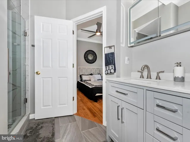 a view of a livingroom with wooden floor a ceiling fan and windows