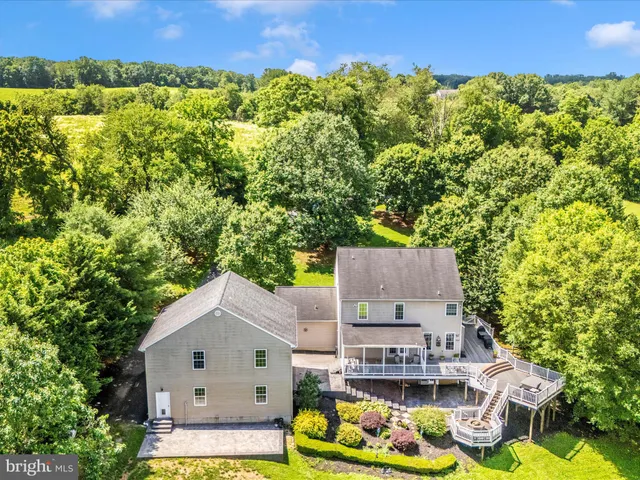 an aerial view of a house with swimming pool and green yard