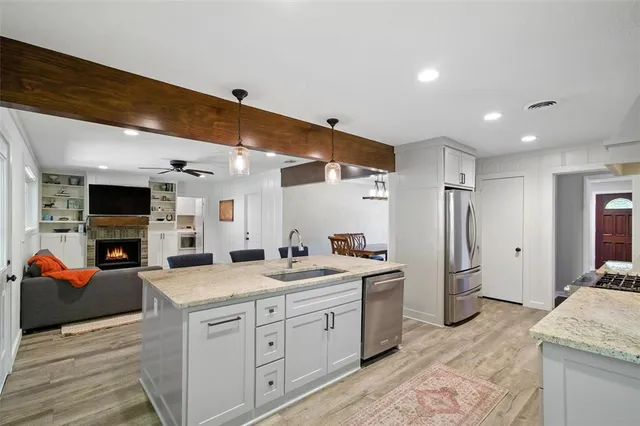 a large white kitchen with a stove a sink dishwasher and a refrigerator with wooden floor