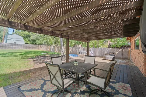 a view of a patio with table and chairs with wooden floor and fence