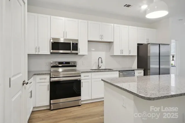 a kitchen with stainless steel appliances granite countertop a sink stove and refrigerator