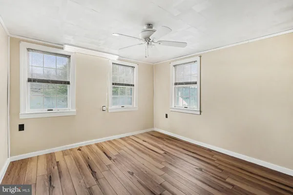 a view of empty room with wooden floor and fan