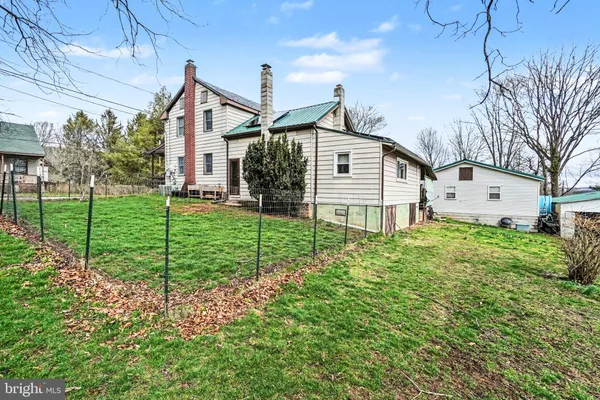a view of a house with a big yard plants and large trees