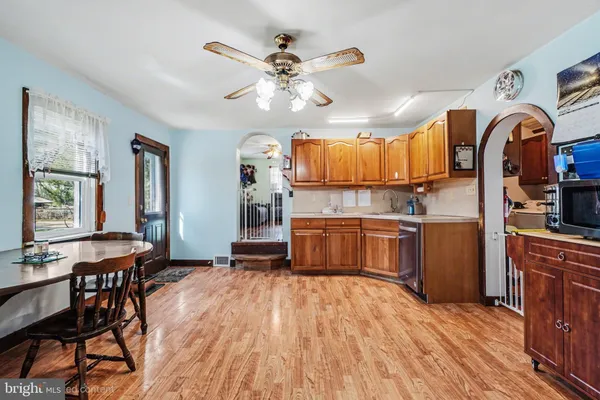 a kitchen with stainless steel appliances kitchen island granite countertop a stove top oven a sink a dining table and chairs with wooden floor