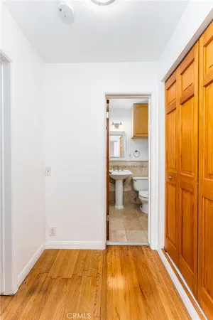 a view of a hallway with wooden floor and a bathroom