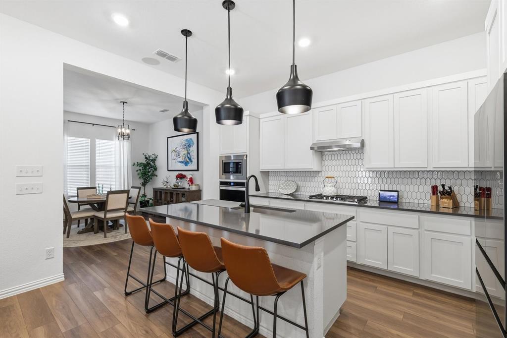 2331 Jack Rabbit Way Northlake, TX 76247 - Photo 14 of 39 a kitchen with stainless steel appliances granite countertop a sink a stove a refrigerator and island with wooden floor