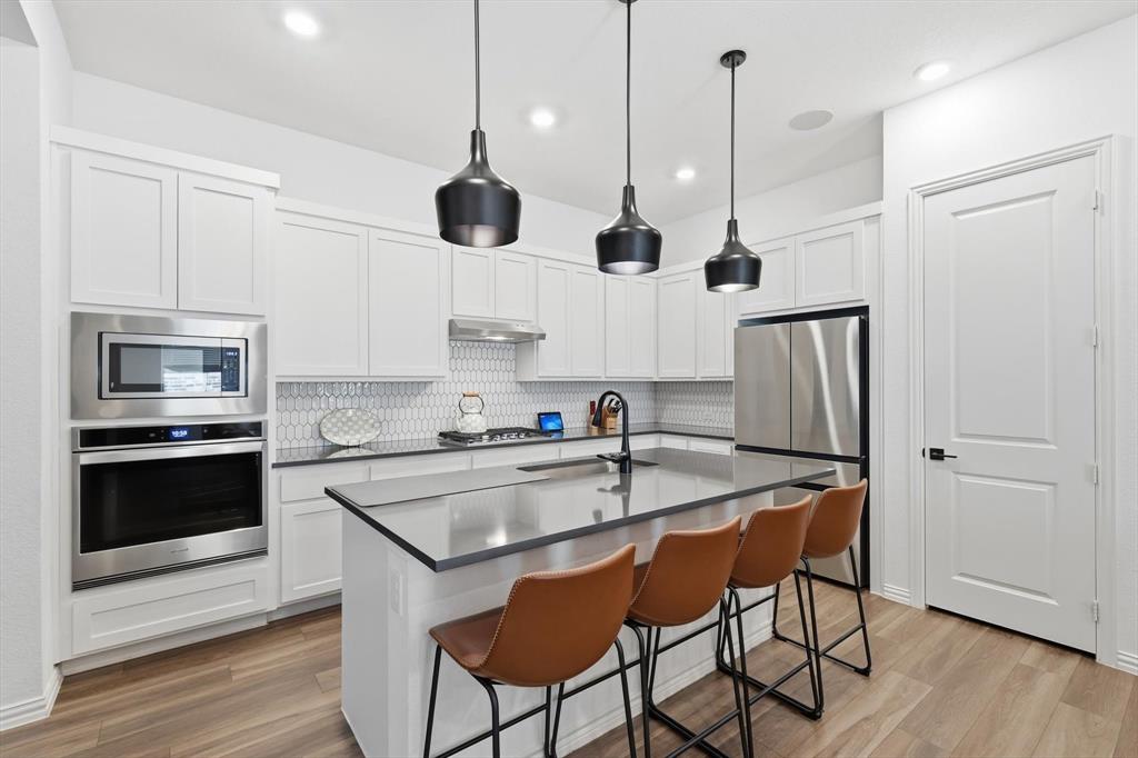 2331 Jack Rabbit Way Northlake, TX 76247 - Photo 15 of 39 a kitchen with stainless steel appliances granite countertop a sink a stove a refrigerator and island with wooden floor