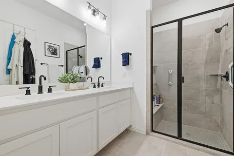 a bathroom with a double vanity sink mirror and shower
