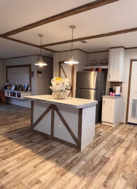 6218 Cr-4813 Pecan Gap, TX 75469 - Photo 28 of 30 Kitchen with decorative light fixtures, light countertops, light wood-style flooring, freestanding refrigerator, and white cabinetry