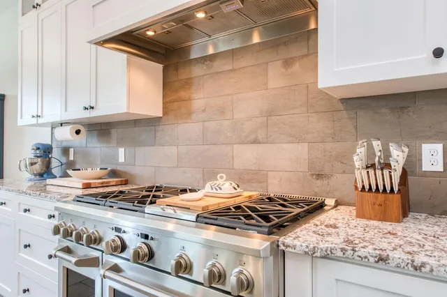 a large kitchen with stainless steel appliances granite countertop a stove a sink and a refrigerator