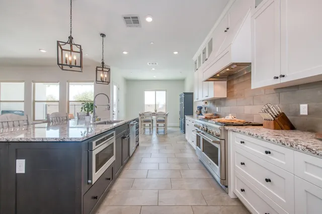 a kitchen with stainless steel appliances kitchen island granite countertop a table chairs and a refrigerator