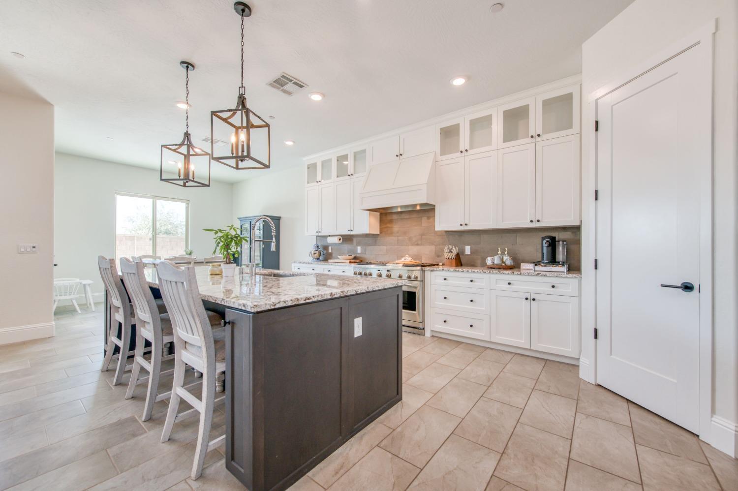 678 Ponderosa Way Madera, CA 93636 - Photo 13 of 38 a kitchen with stainless steel appliances kitchen island granite countertop a table chairs and a refrigerator