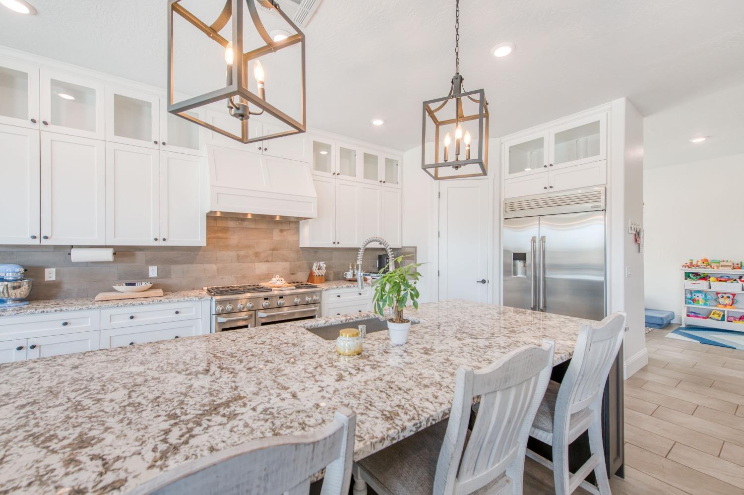 678 Ponderosa Way Madera, CA 93636 - Photo 14 of 38 a kitchen with granite countertop a table chairs stove and refrigerator