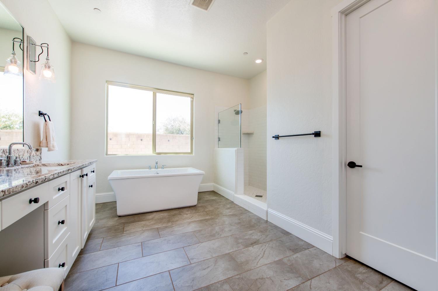 678 Ponderosa Way Madera, CA 93636 - Photo 28 of 38 a bathroom with a granite countertop double vanity sink a bathtub and window