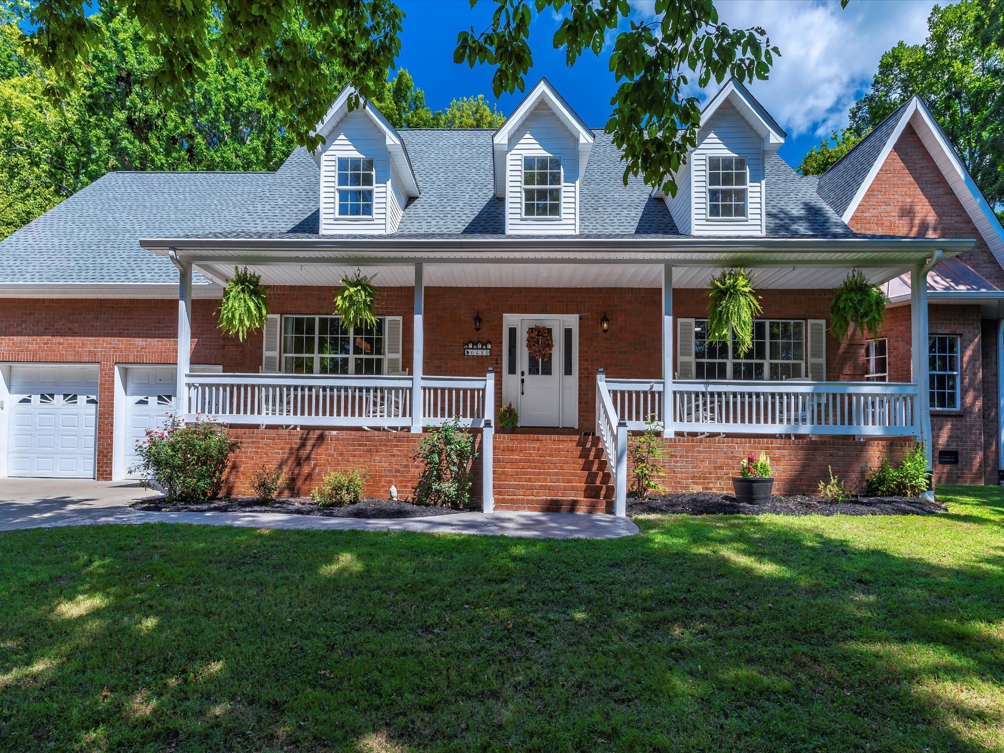a front view of a house with a yard and potted plants