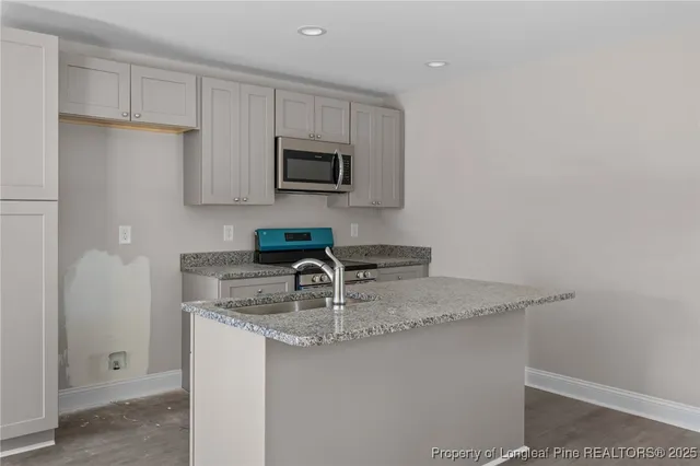 a kitchen with stainless steel appliances granite countertop a sink a microwave a refrigerator and white cabinets
