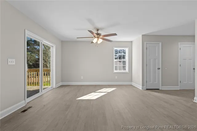 an empty room with windows and ceiling fan