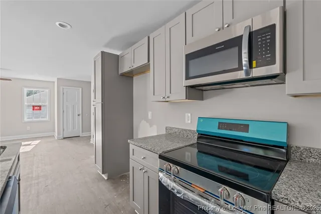 a kitchen with stainless steel appliances white cabinets and a stove top oven