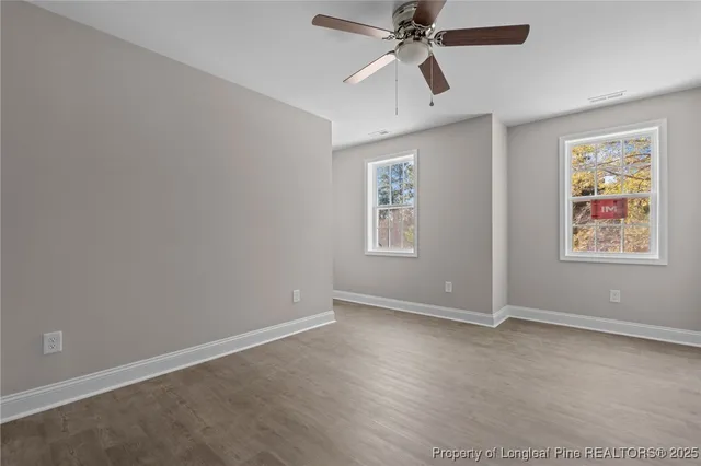 an empty room with windows and fan