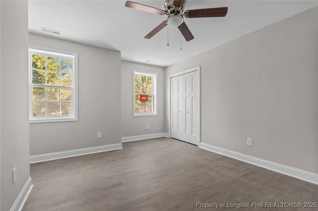 an empty room with windows and fan