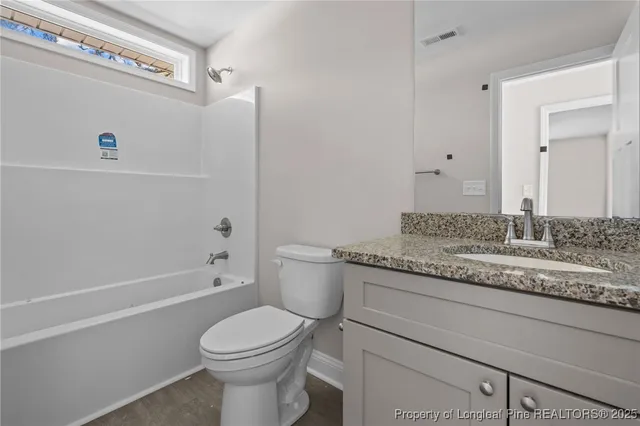 a bathroom with a granite countertop toilet a sink and bathtub