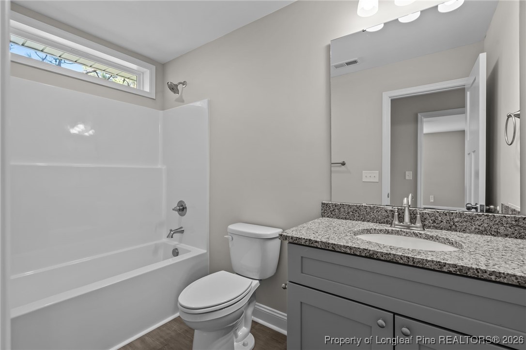 1010 Saunders Avenue Aberdeen, NC 28315 - Photo 31 of 44 a bathroom with a granite countertop toilet a sink and a mirror