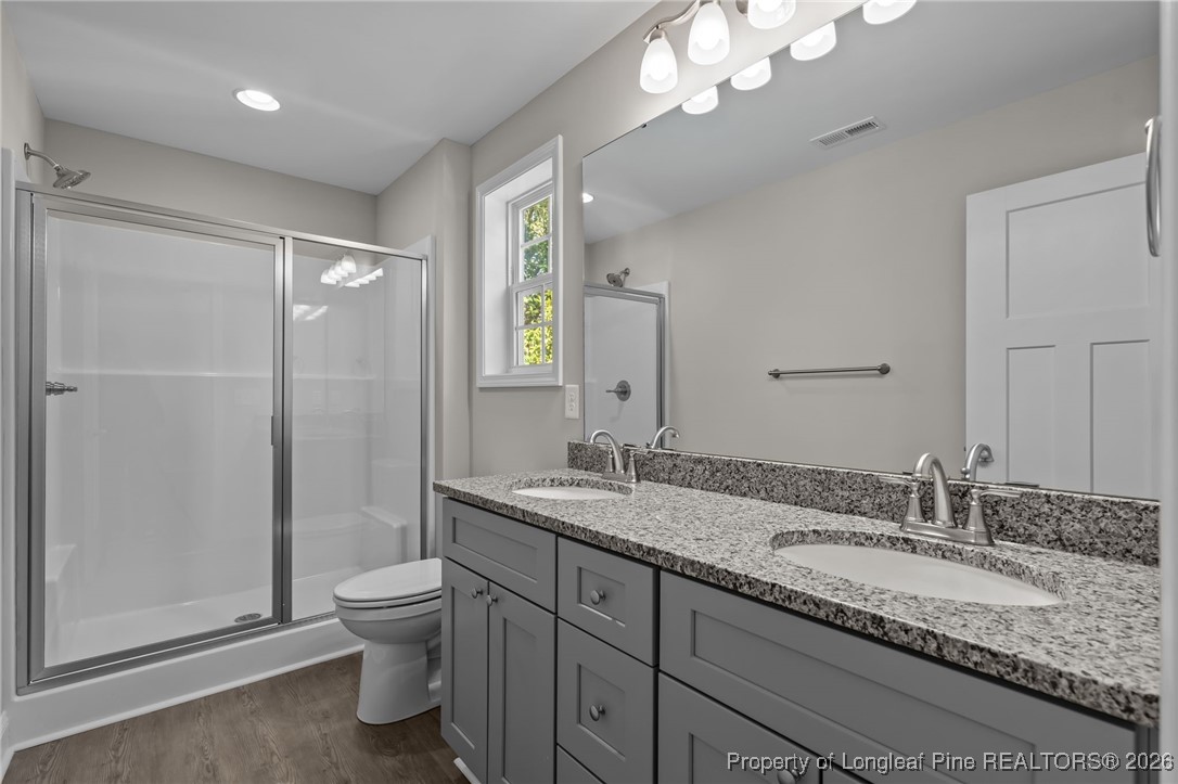 1010 Saunders Avenue Aberdeen, NC 28315 - Photo 35 of 44 a bathroom with a granite countertop sink a toilet a mirror and shower
