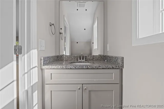 a bathroom with a granite countertop sink and a mirror