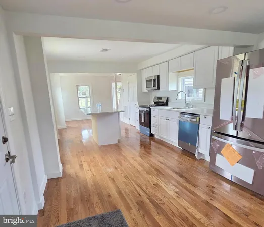 a large kitchen with a wooden floor and a refrigerator